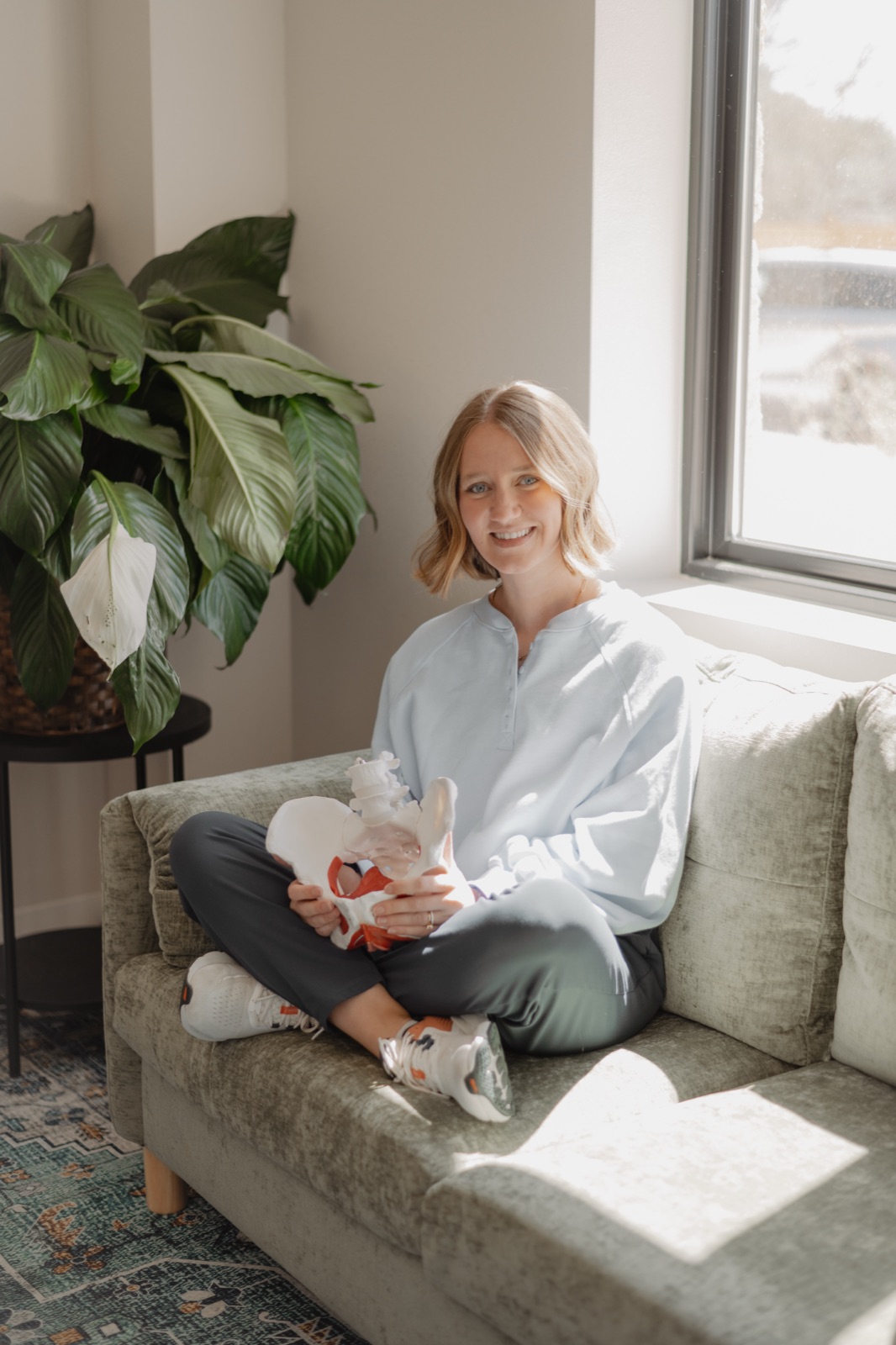 Natalie sitting on a couch with a pelvic anatomy model